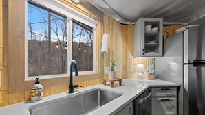 Cocina moderna con un lavamanos grande, paneles de madera, un armario empotrado y un refrigerador de acero inoxidable.
