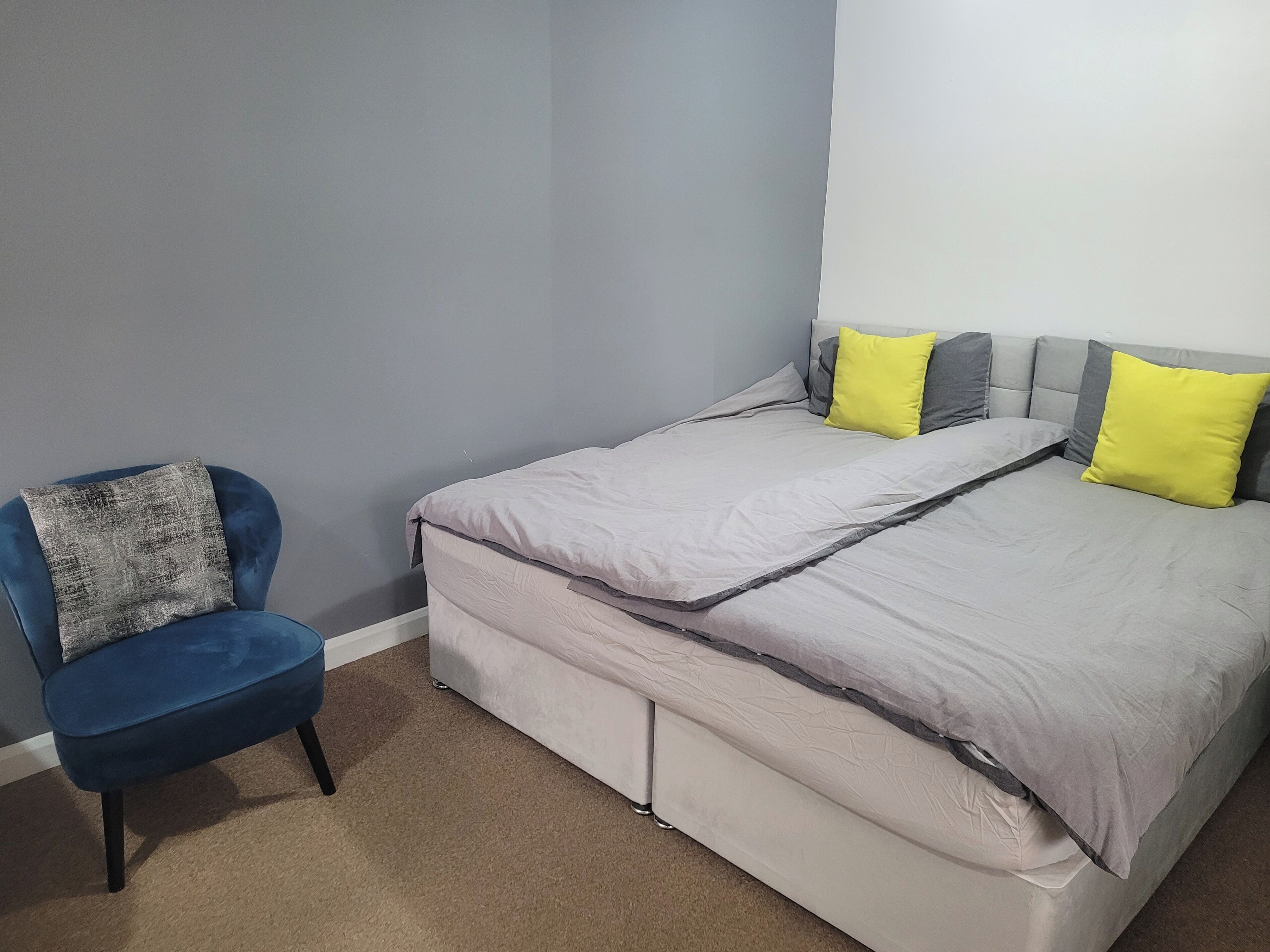 A bedroom with a bed, a chair, and a wall.