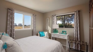 A bedroom with a bed, a nightstand, a dresser, and a window with curtains.