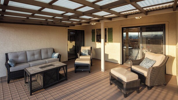 A covered patio area with a sofa, chairs, and a table.
