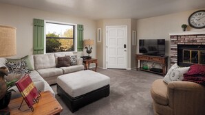 A living room with a sofa, ottoman, and a television.