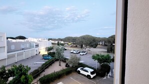 Ein Parkplatz mit mehreren Autos, ein Gebäude mit flachem Dach und Bäumen im Hintergrund.