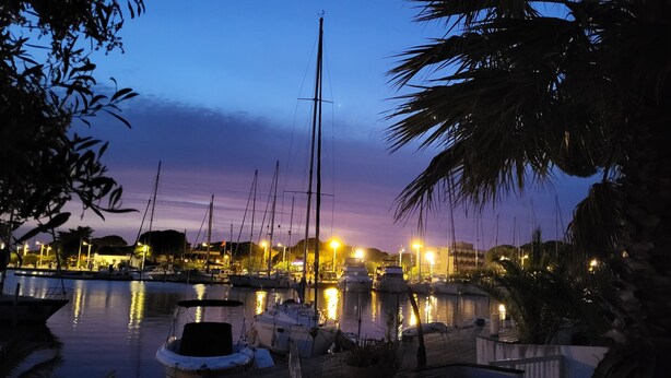 Ein Hafen im Abenddämmerung mit vertäuten Booten und beleuchteter Umgebung.