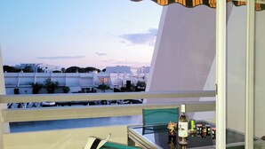 Ein Balkon mit Glastisch, einer Flasche und einem Stuhl.