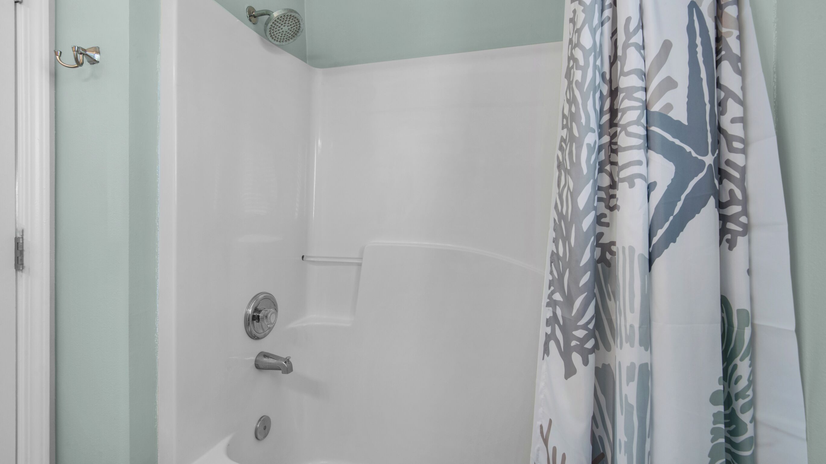 A shower with a handheld showerhead, a wall-mounted faucet, and a control knob.