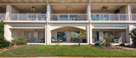A two-story building with balconies, a covered front porch, and a lawn.