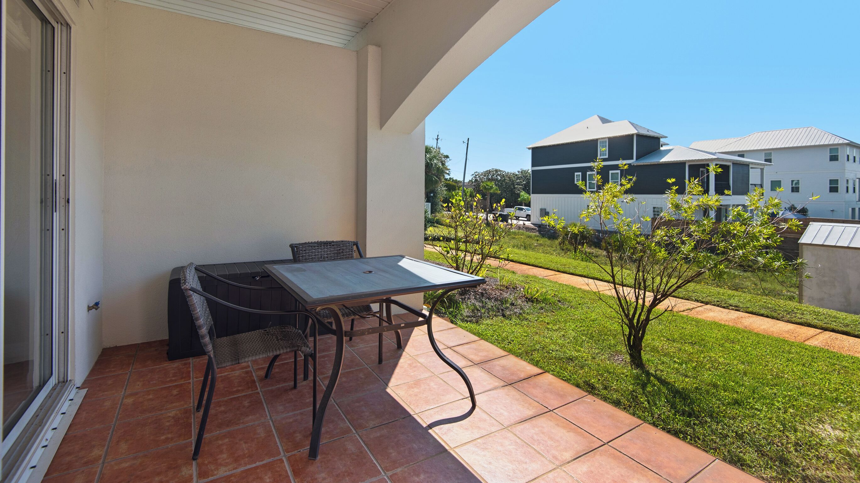 A balcony with a table and chairs, a view of a residential area, and a clear sky.