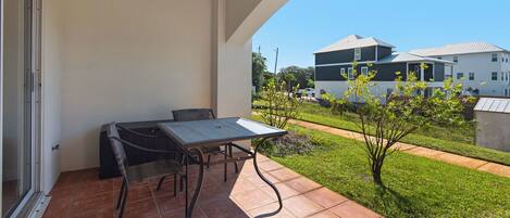A balcony with a table and chairs, a view of a residential area, and a clear sky.