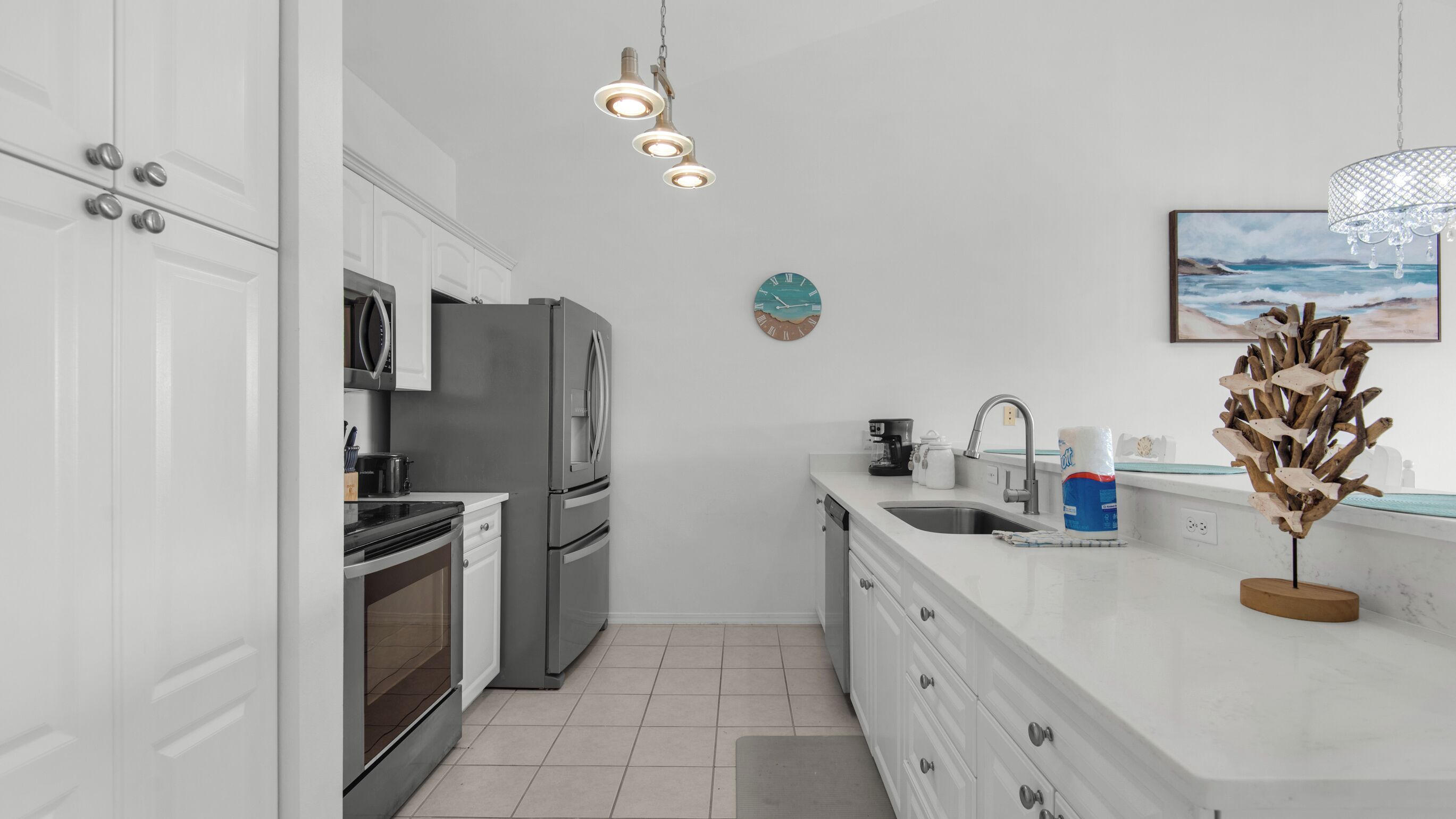 A modern kitchen with white cabinets, stainless steel appliances, and a marble countertop.