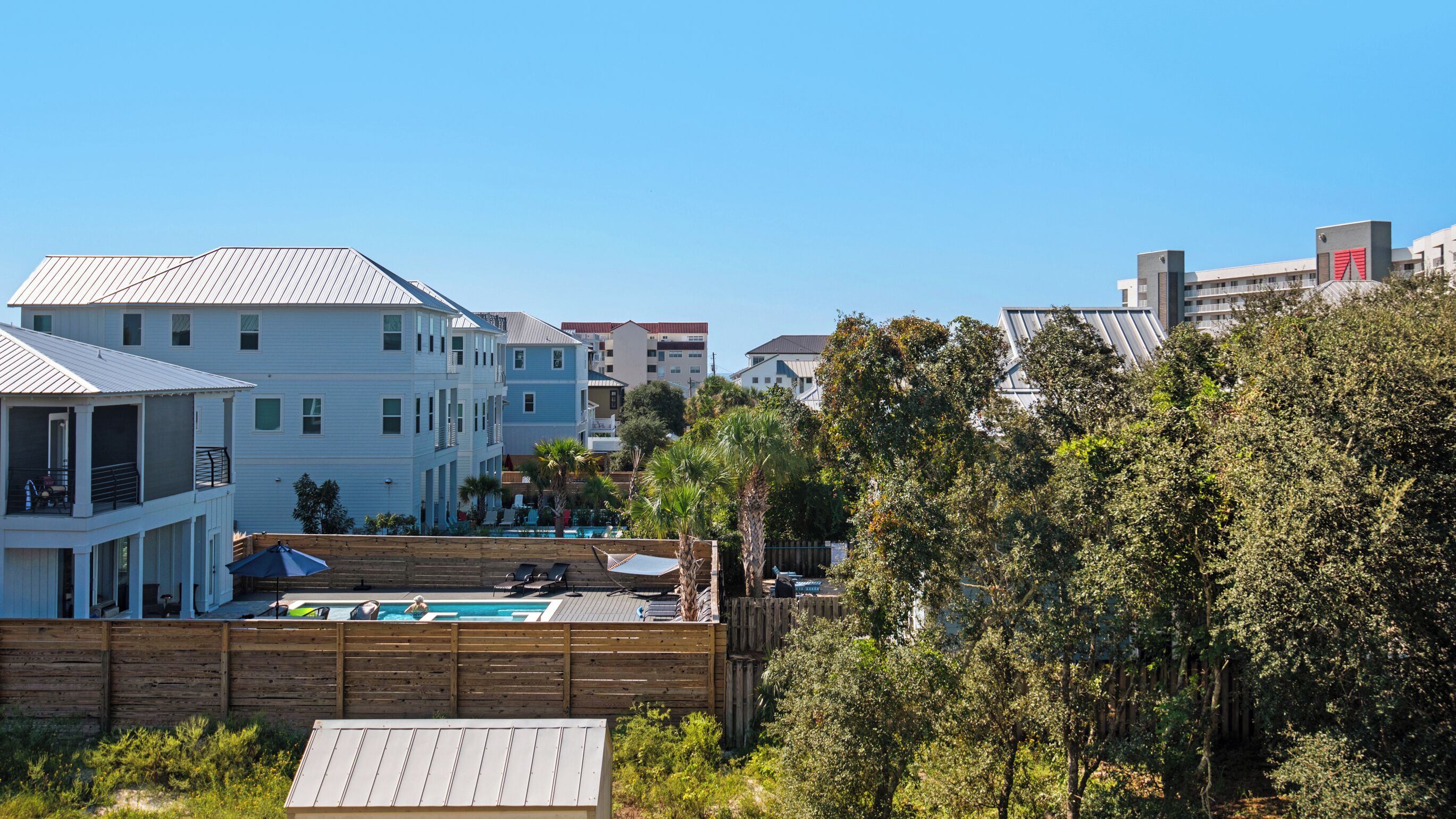 A residential area with multiple two-story houses, a wooden fence, and a swimming pool.