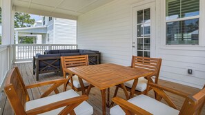Enjoy meals and conversations in a shaded seating area with a table and chairs, a grill, and a secure, space.