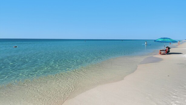A beach with clear turquoise water, a sandy shore, and a few people. - 1-minute to the Boat Launch, Boat Parking Under Home, An Experience For Less (Santa Rosa Beach)