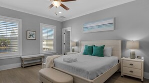 Relax in this serene bedroom with a large bed, bedside tables, and a ceiling fan.
