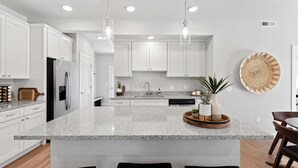 A modern kitchen with white cabinetry, granite countertops, and pendant lighting. - Chic Bozeman Getaway - Minutes from Downtown! (Bozeman)