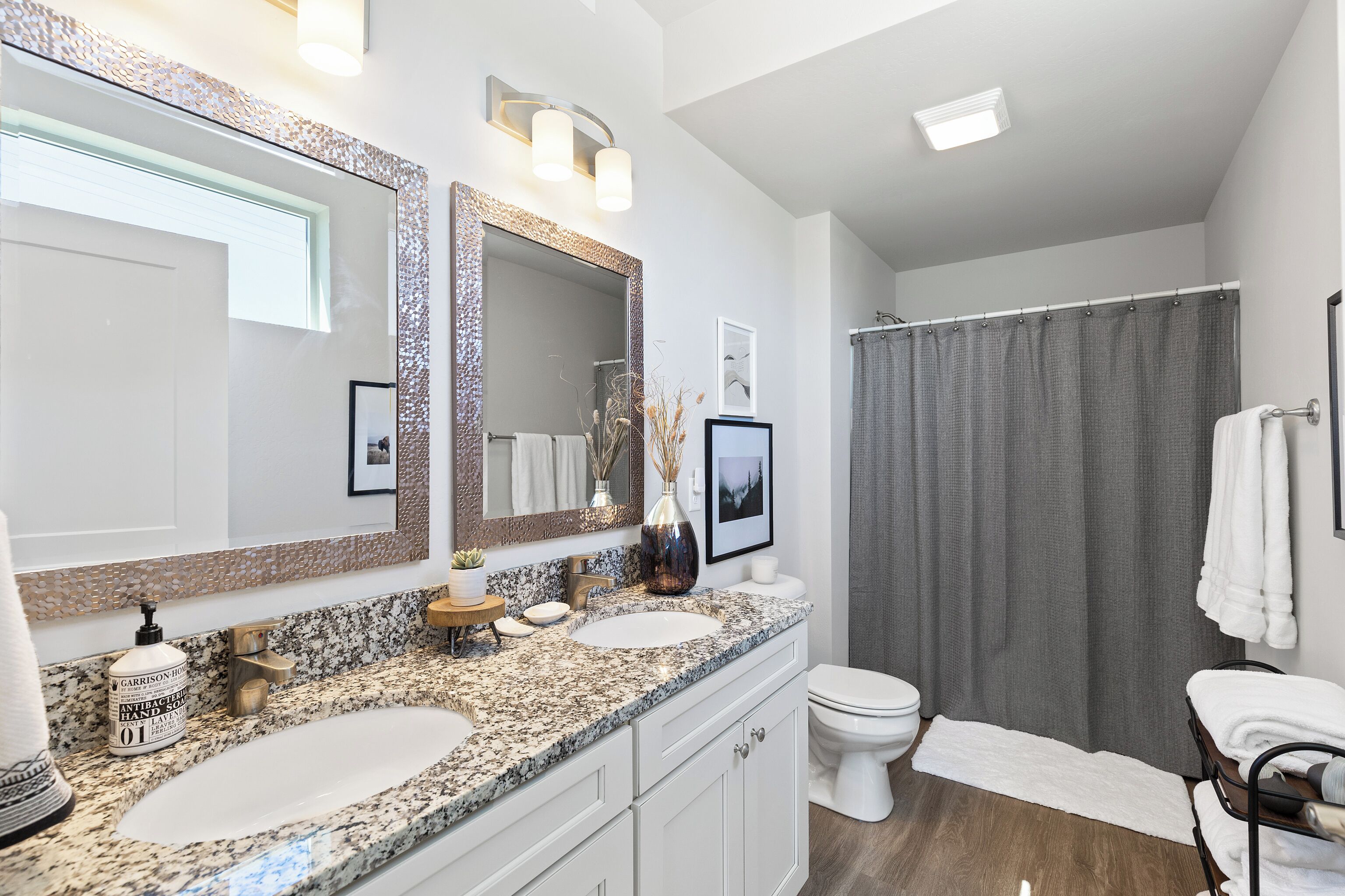 Un baño moderno con dos lavamanos, un espejo grande y una cortina de ducha.