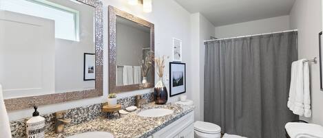 Un baño moderno con dos lavamanos, un espejo grande y una cortina de ducha.