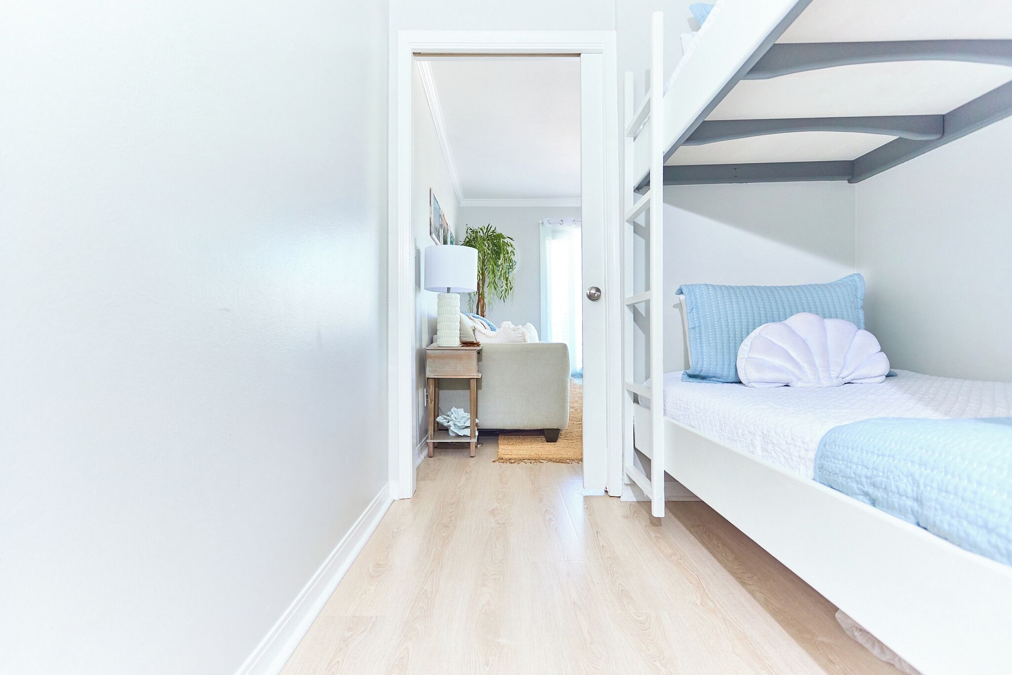 A compact bedroom with a bunk bed, a bedside table with a lamp, and a small desk with a chair.