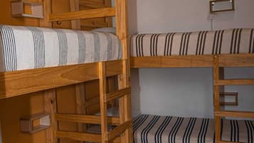 Dormitorio con literas de madera y ropa de cama a rayas.