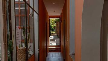 A corridor with tiled flooring, a window with a view of greenery, and a door leading to an outdoor area.