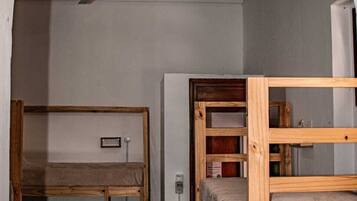 Una habitación con literas, ventilador de techo y una ventana pequeña.