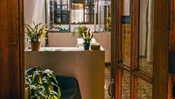 Una habitación con piso estampado, una puerta de madera, una ventana con vistas y una planta en maceta.