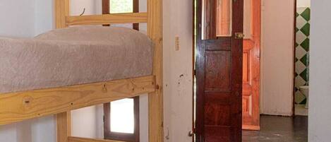 Una cama individual en un dormitorio con una escalera que lleva a una puerta.