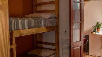 Una litera con escalera de madera, una silla pequeña y una puerta que da a otra habitación.