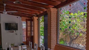 Un comedor con una mesa y sillas de madera, una pared de ladrillo y una ventana que da a zonas verdes.