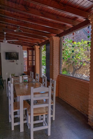 Un comedor con una mesa y sillas de madera, una pared de ladrillo y una ventana que da a zonas verdes.