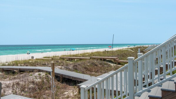 A beach view with wooden walkways and a white railing.