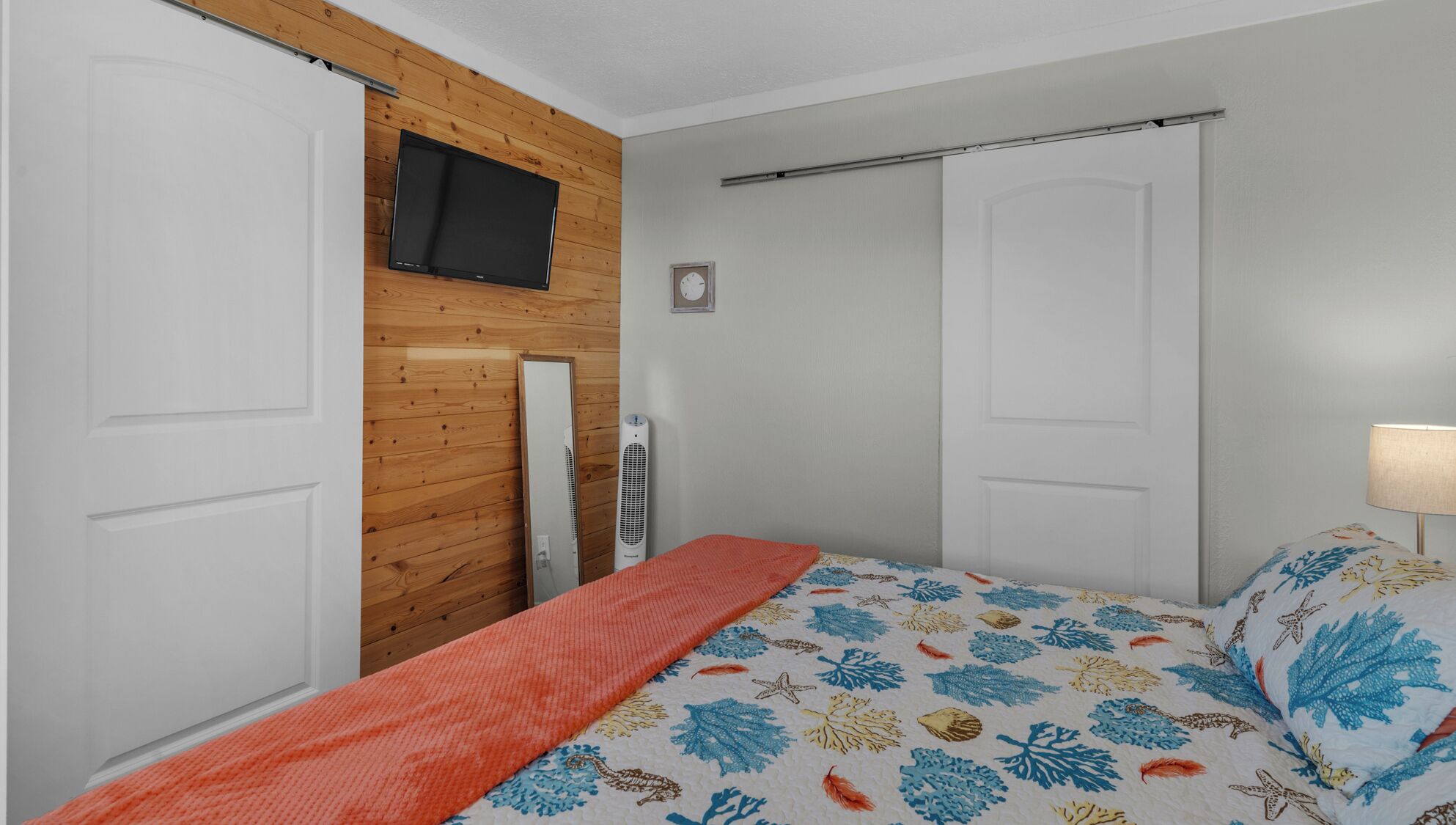 Ein Schlafzimmer mit einem Bett, einem an einer Holzwand befestigten Fernseher und einer Heizung.