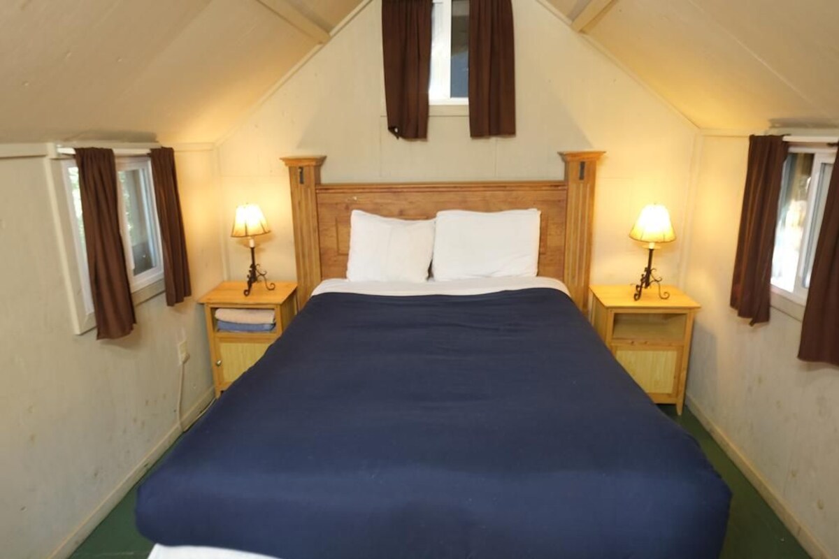 A single bed with a wooden headboard in a room with two bedside tables, each with a lamp.