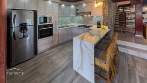 Une cuisine moderne dotée d’appareils électroménagers en acier inoxydable, d’un îlot en marbre et d’une cuisinière intégrée.