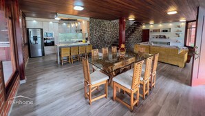 Une cuisine moderne avec un mur en pierre, une table à manger en bois et des chaises en osier.