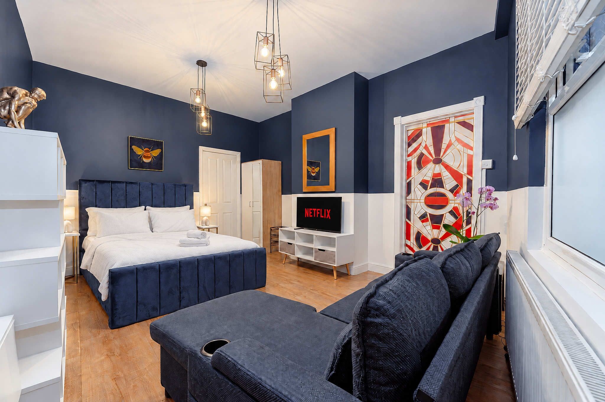 A modern bedroom with a bed, bedside tables, a TV, and a decorative door.