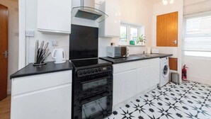 Een moderne keuken met een zwarte kookplaat, witte kastjes en een magnetron.