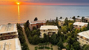 Un quartier résidentiel en bord de mer, avec des bâtiments modernes, une vue dégagée sur la mer et un magnifique coucher de soleil.