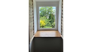 Ein Eckzimmer mit eingebauter Bank und Fensterblick auf einen Garten.