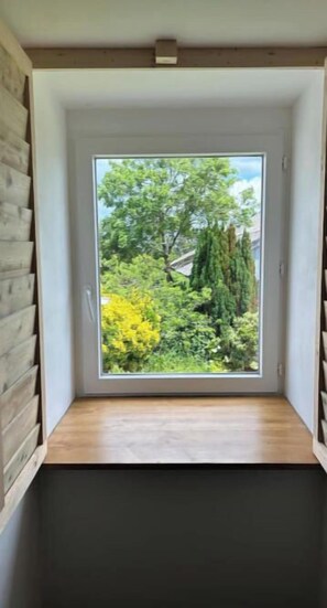 Une pièce dotée d’une grande fenêtre, de murs en bois et d’un plancher foncé.