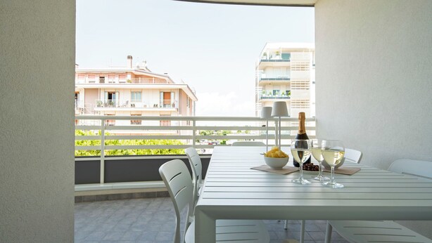Un balcon avec une table dressée pour deux personnes, une bouteille de champagne et un bol de chips.