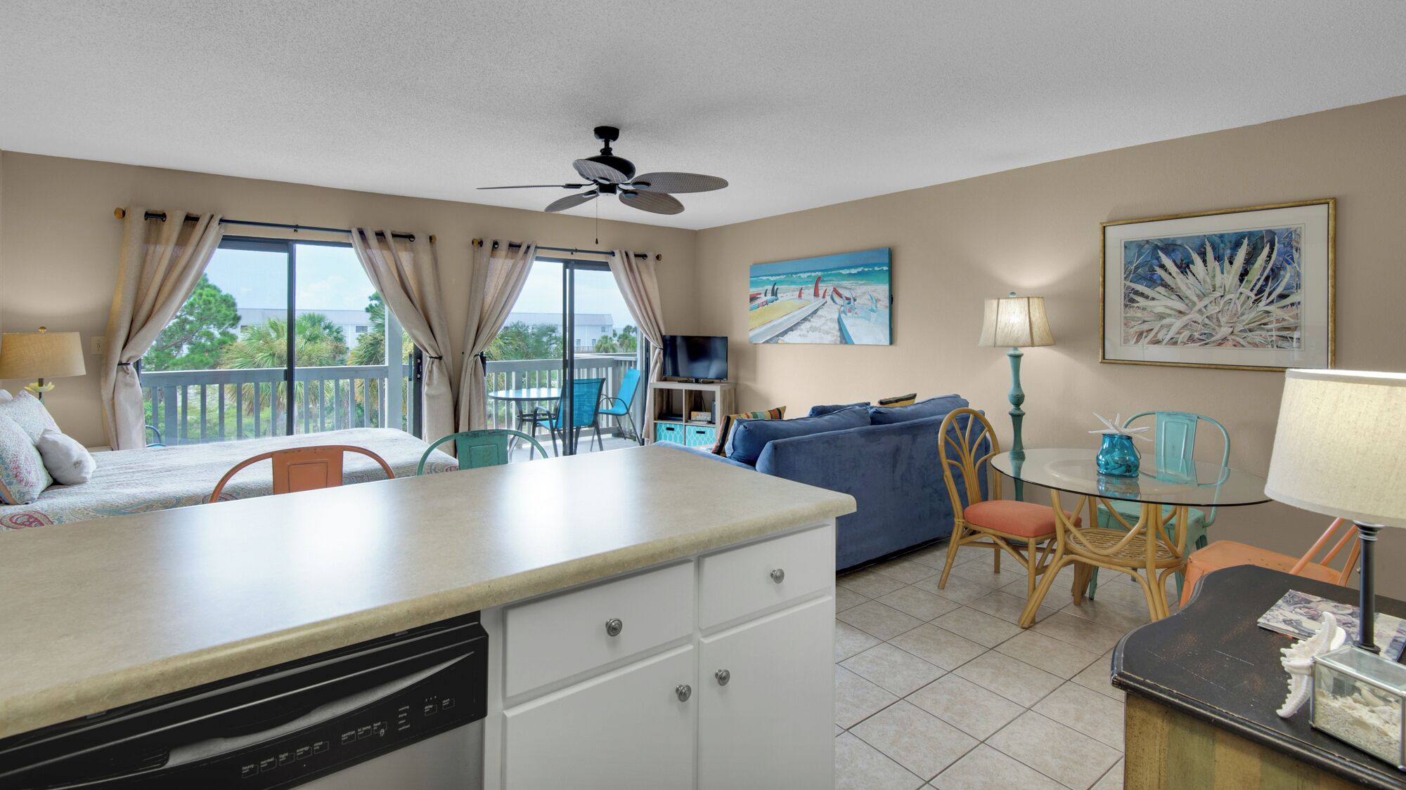 A compact hotel room with a kitchenette, a dining area, a sofa, and a TV.