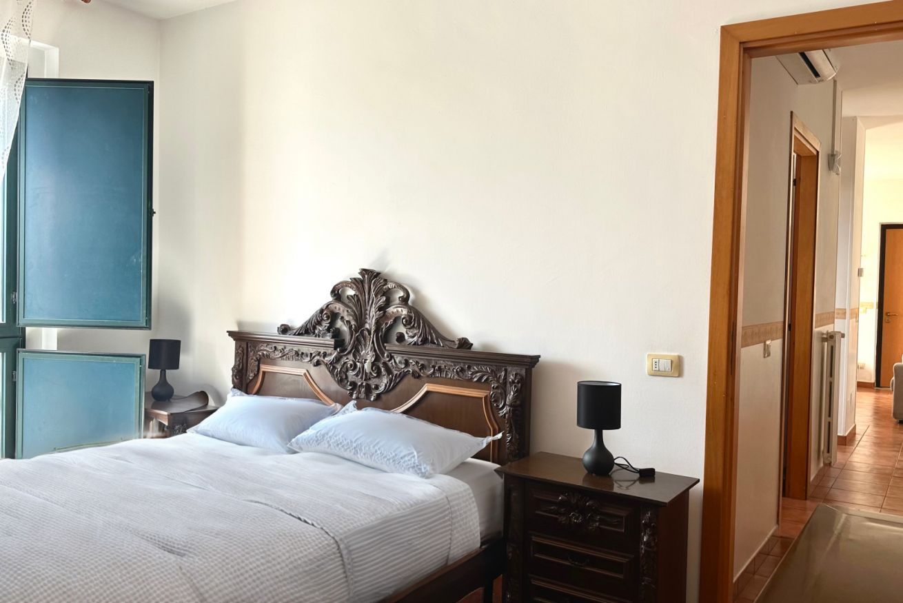 Un dormitorio con una cama grande, un cabecero de madera, una mesita de noche y un armario.