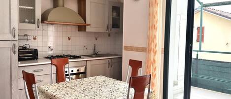A kitchen with a table and chairs, a stove, and a clock on the wall.