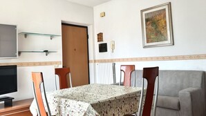 Een eetruimte met een tafel, stoelen, een televisie en een bank.