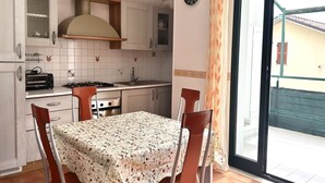 Een keuken met een tafel, stoelen, een fornuis en een klok aan de muur.