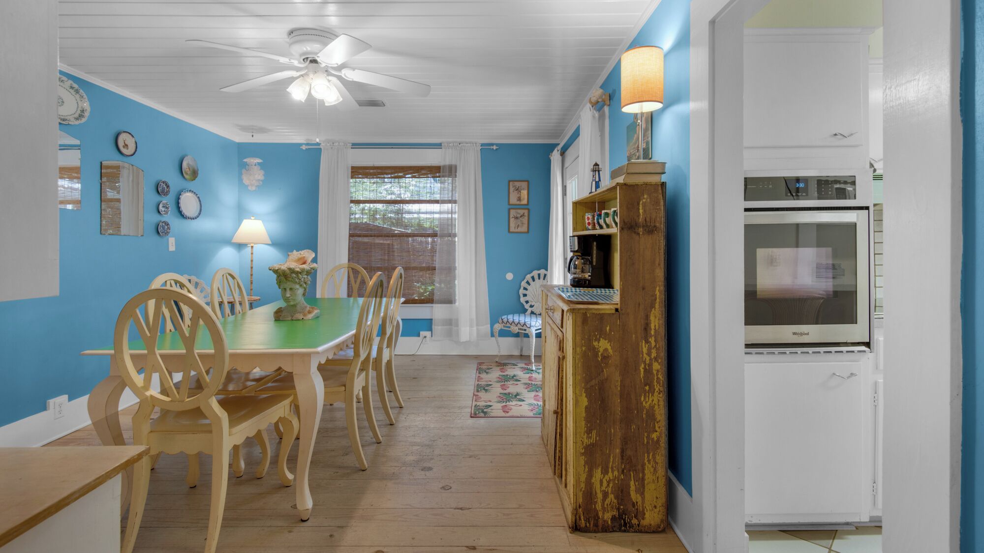 A dining area with a table and chairs, a ceiling fan, and a refrigerator.