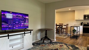 A modern living room with a flat-screen TV, a wooden coffee table, and a patterned rug. - Cute McRee Manor with large screened porch (Valdosta)