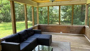A covered outdoor seating area with a wooden ceiling, large windows, and a ceiling fan. - Cute McRee Manor with large screened porch (Valdosta)