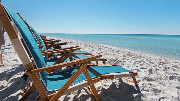 A row of wooden beach chairs with blue cushions on a sandy beach, facing a calm sea under a clear sky. - 2 Minutes to the Gulf - Sleeps 10 in Seagrove Beach (Santa Rosa Beach)