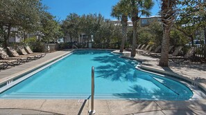 Une piscine avec des chaises longues et des palmiers.